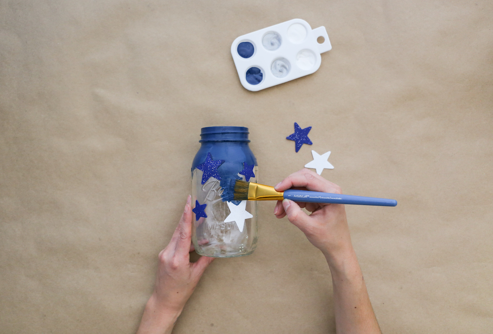 Painting jar with blue paint over stars
