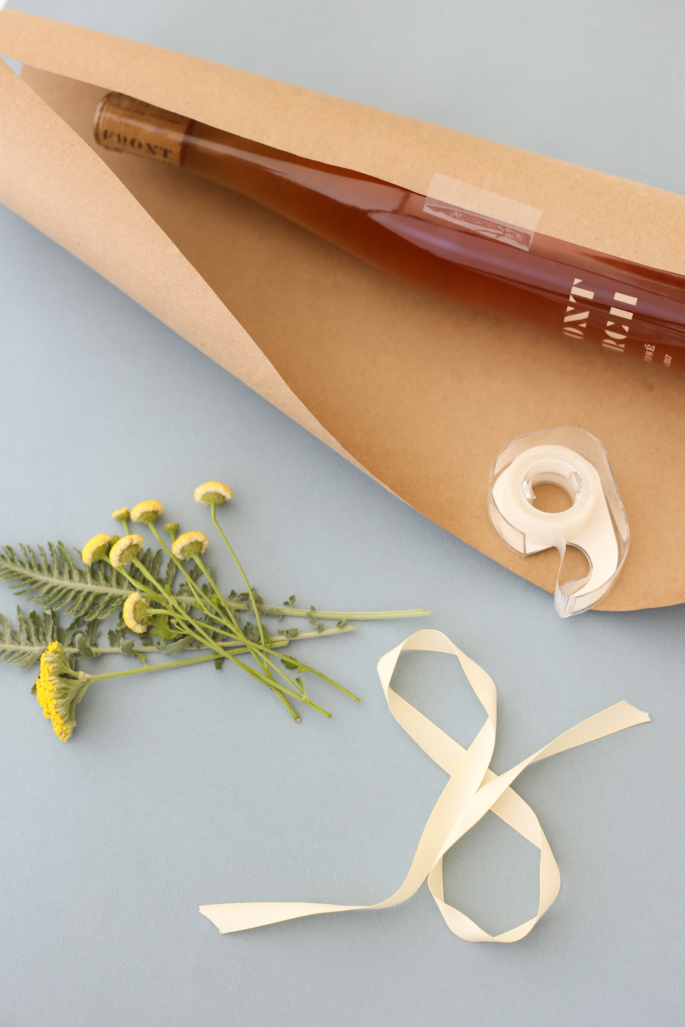 Wine bottle in craft paper with tape, flowers, and ribbon